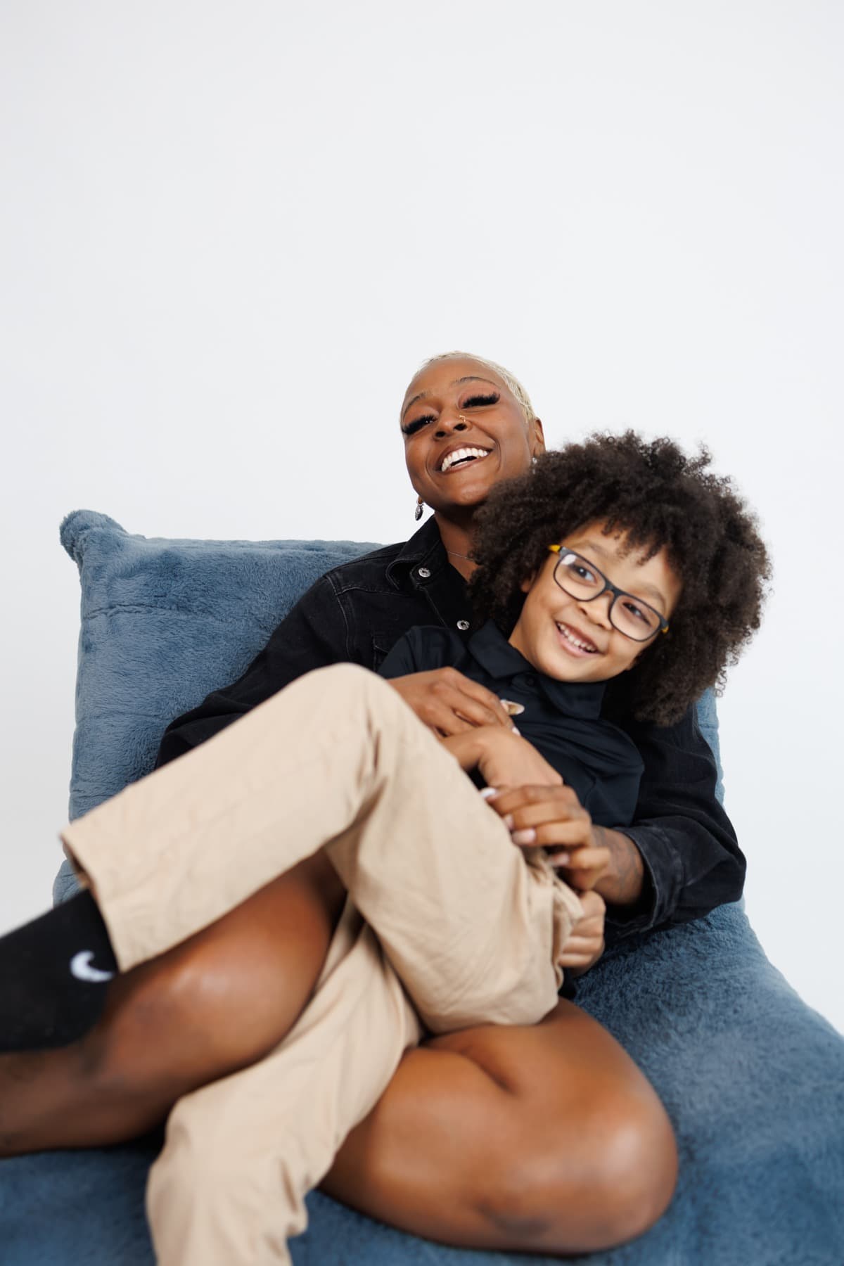 The founder and her son smiling together on a blue chair.